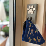Dog tag with paw print design and 'Winnie' engraved, attached to a door handle.